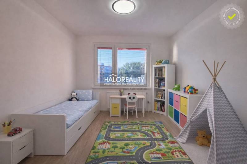 A children's room with a colorful carpet, white furniture, and a wooden decor floor.