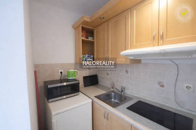 Kitchen corner in a studio apartment with a microwave and wooden cabinets.