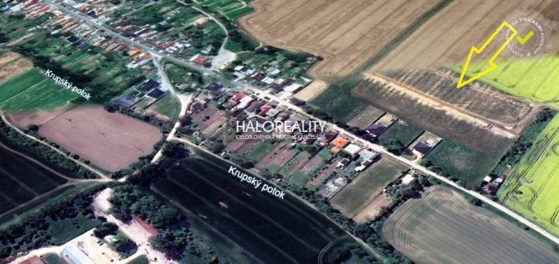 A view of plots prepared for housing in Horná Krupá surrounded by fields and houses.