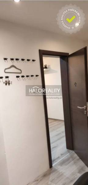 The hallway in a 3-room apartment with a wooden decor floor and wall hooks.