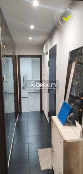 A narrow hallway in a 3-room apartment with black floor tiles and a wall mirror.