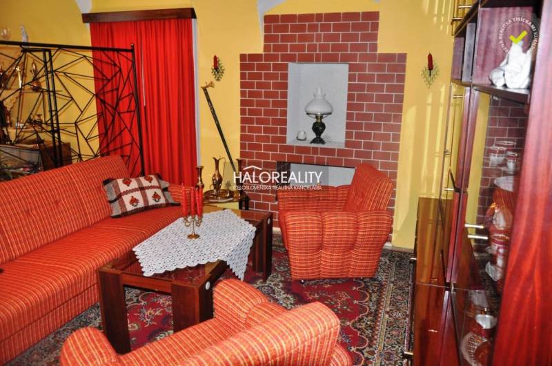 Living room with red sofas, carpet, and a brick fireplace in a family house.