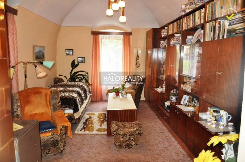 Living room with antique furniture, shelves, and books. Next to it is the entrance to the family house.