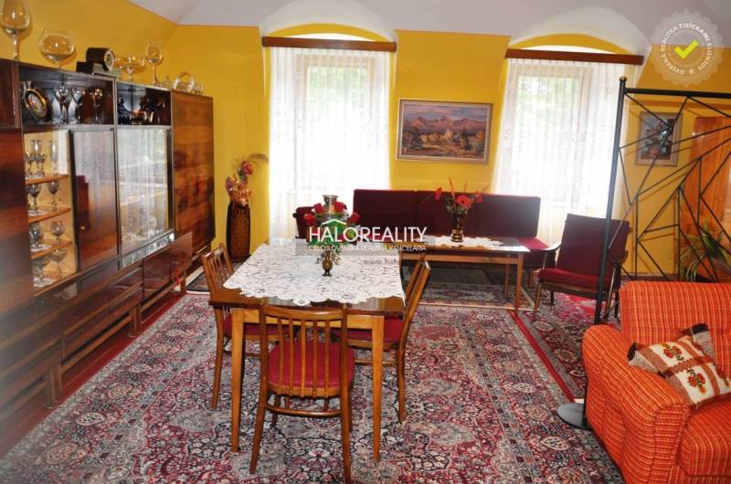 Living room in a family house with a carpet, display cabinet, and floral decoration.
