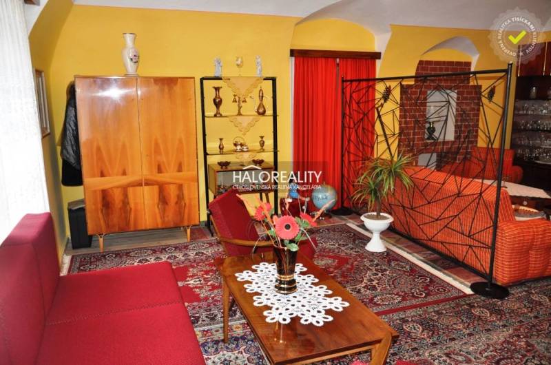 Interior of a family house with retro furniture, red curtains, and a carpet with an oriental pattern.