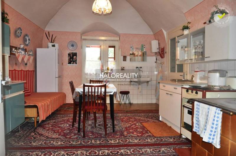 A kitchen in a family house with vintage decor, a wooden cabinet, and carpets.