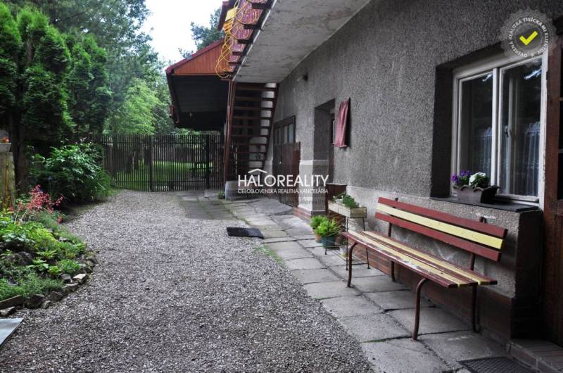 The courtyard of a family house in Nálepkovo with a bench and a garden full of greenery.