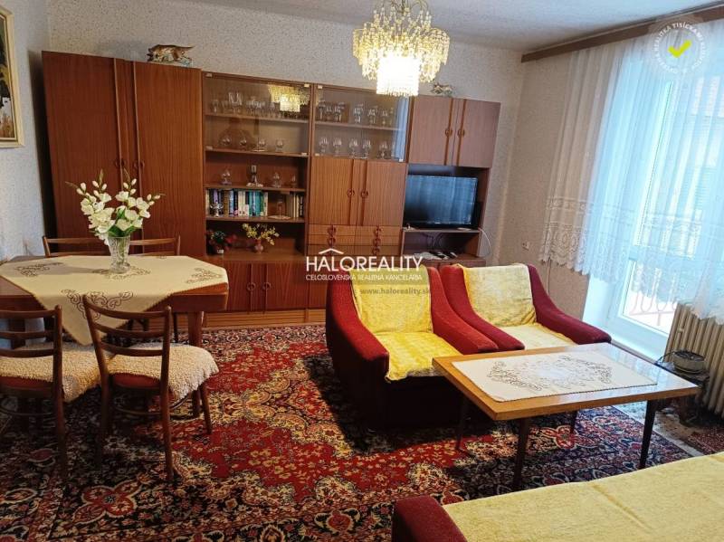 Living room in a two-room apartment with wood decor and flowers on the table.