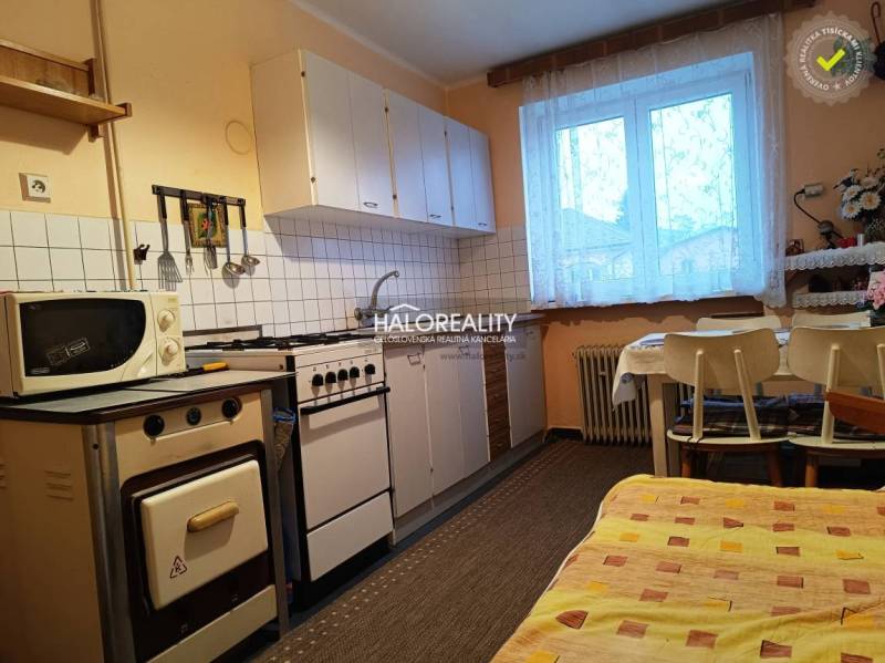Kitchen in a 2-room apartment with a gas stove, dining table, and microwave.