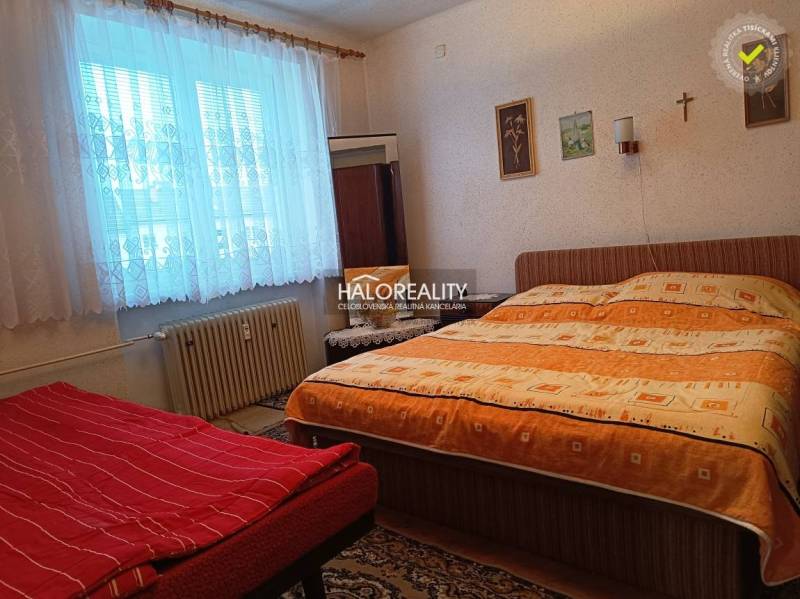 Bedroom in a 2-room apartment with a bed, carpet, and window radiator.