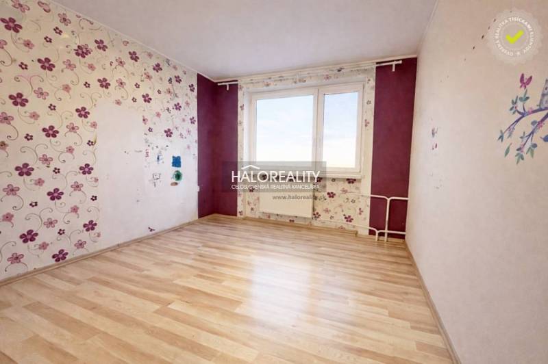 A room in a 4-room apartment with floral wallpaper and a wood-patterned floor.