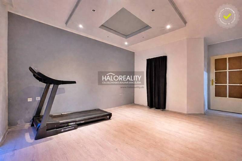 Fitness room in a 4-room apartment with a wooden decor floor, treadmill.