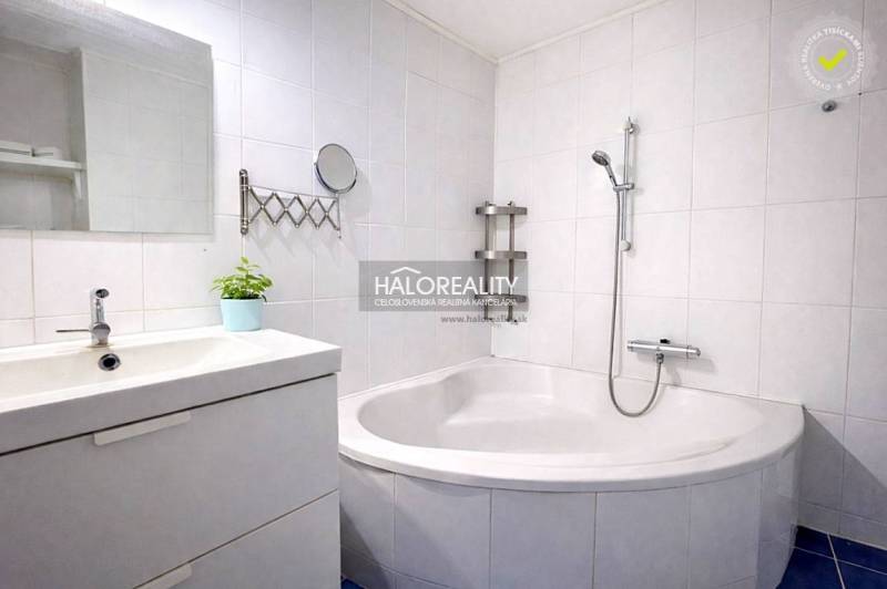 Bathroom with a corner bathtub and a mirror in a 4-room apartment, white tiles.