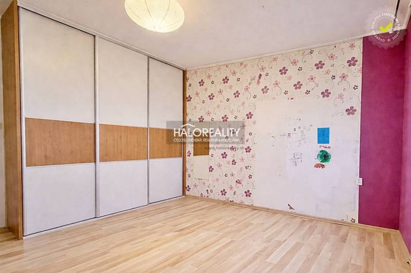 A room in a 4-room apartment with a floor featuring a wood decor and wallpaper with a floral pattern.