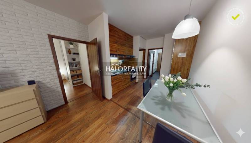 Interior of a 3-room apartment with decorative walls, wood-patterned flooring, and a glass table.
