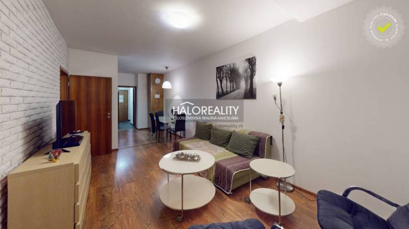 Living room in a 3-room apartment with a wooden decor floor and a brick wall.