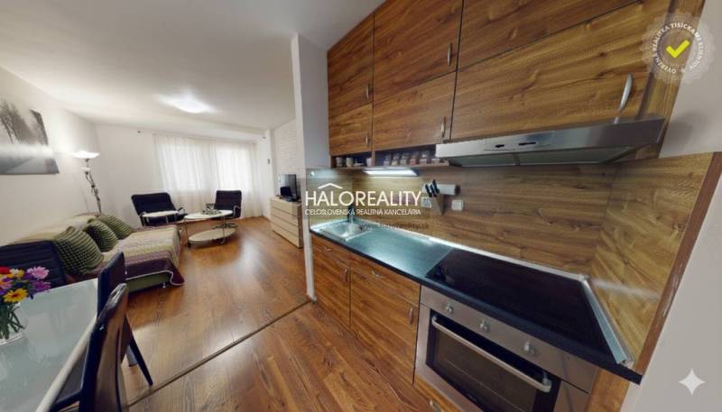 A kitchen with a wooden decor floor, connected to the living room in a 3-room apartment.
