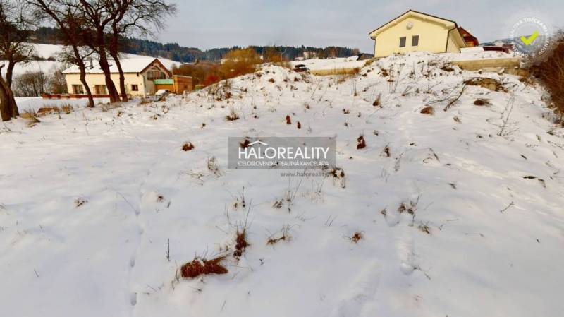 A snowy residential plot in Liptovské Beharovce, with a view of the surrounding hills and houses.