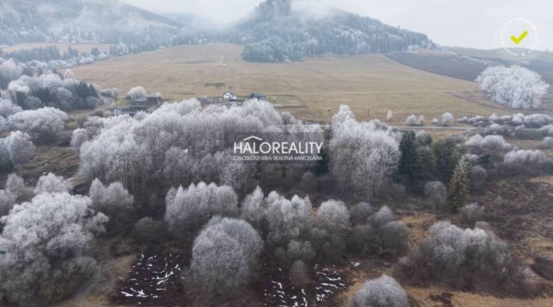 Snow-covered recreational plots in Liptovský Ján surrounded by a winter landscape and deciduous trees.