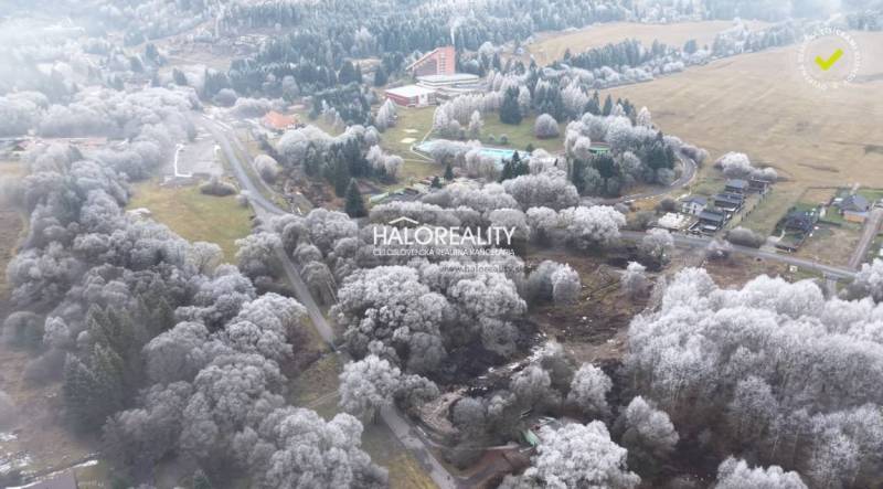 Winter landscape with recreational plots in Liptovský Ján surrounded by snow-covered trees.