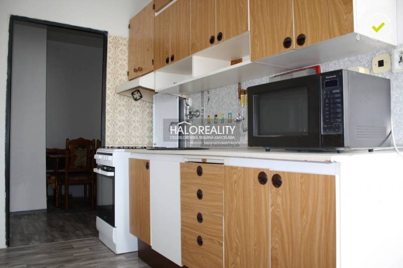 A kitchen in a 2-room apartment with a wooden decor floor and a vintage backsplash.