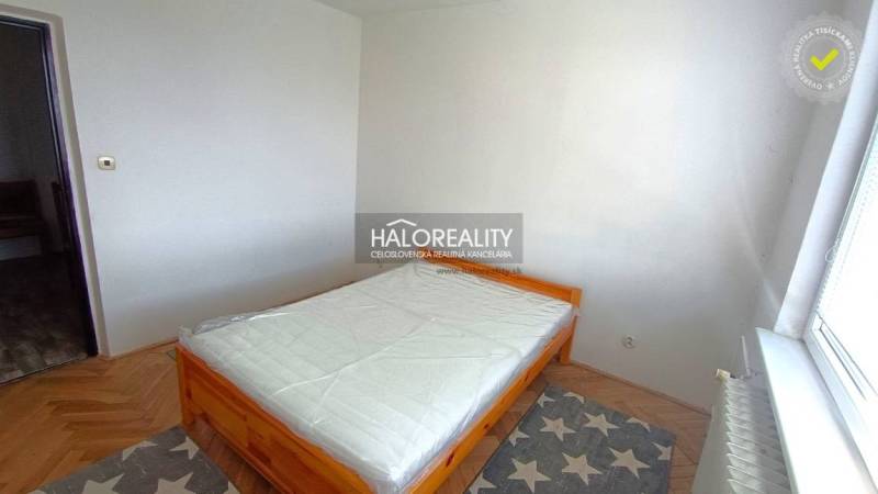 A bedroom in a two-room apartment with a bed and a wooden decor floor.