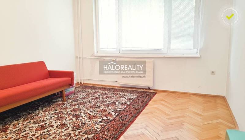 Living room in a 3-room apartment with a red sofa and patterned carpet.
