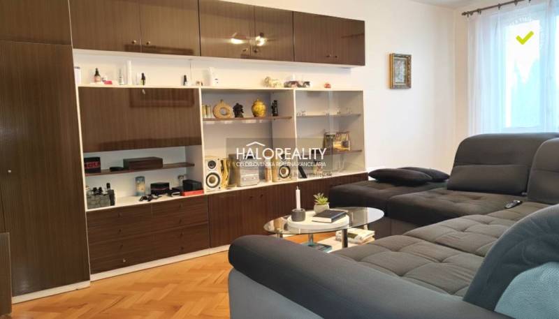 Living room in a 3-room apartment with a sofa, shelves, and a floor with a wooden decor.
