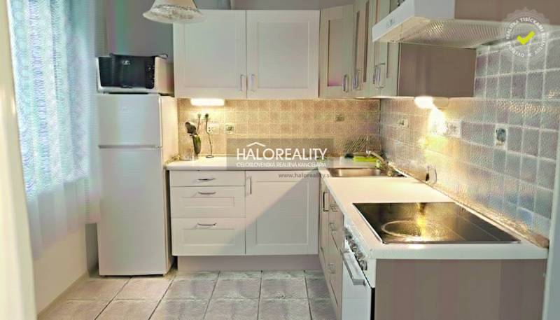 A kitchen in a 3-room apartment with a light-colored kitchen unit, stove, and refrigerator.