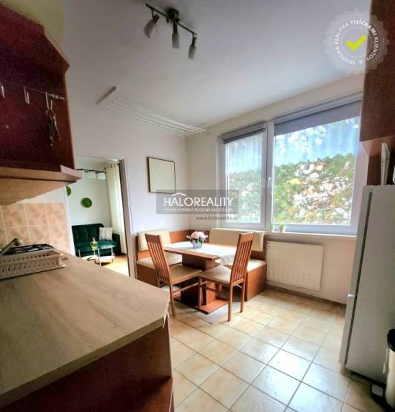 A kitchen in a studio apartment with a corner bench, a dining table, and large windows.