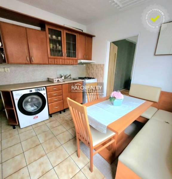 A kitchen in a studio apartment with wooden furniture and ceramic flooring.