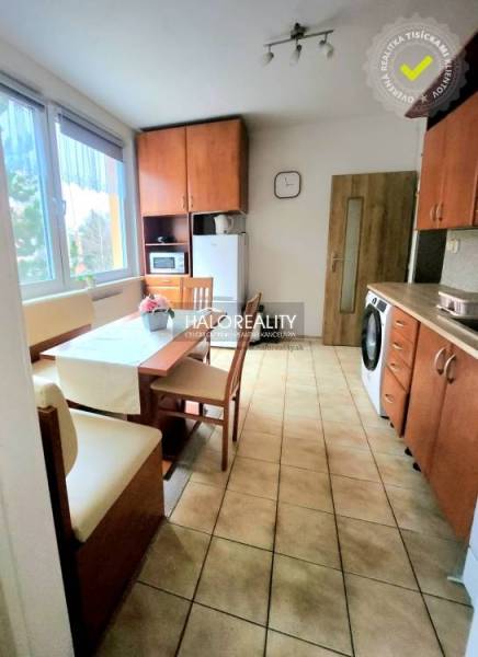 A kitchen in a one-room apartment with a dining table, a dishwasher, and wooden decor furniture.