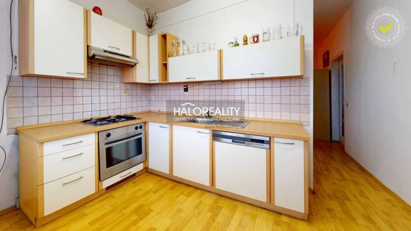A kitchen in a 3-room apartment with a wood-patterned floor and built-in appliances.