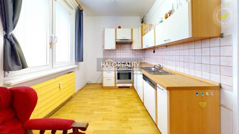 A kitchen in a 3-room apartment with a wooden decor floor and a simple kitchen unit.