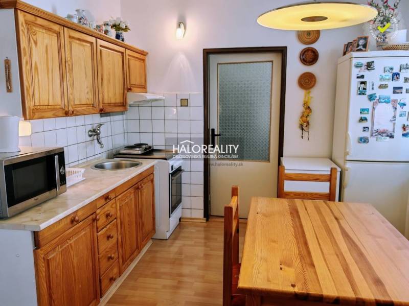 A kitchen in a 3-room apartment with a wooden decor floor and wooden furniture.