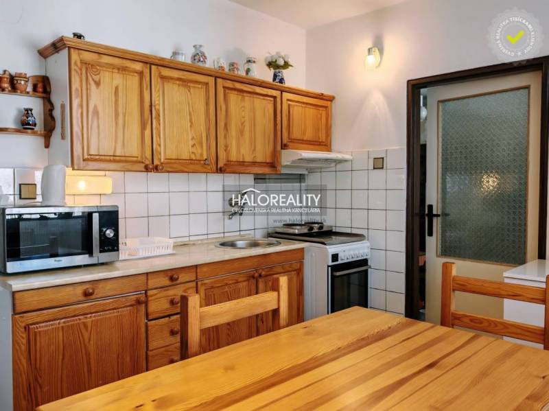 A kitchen in a 3-room apartment with wooden furniture and white tiles above the work surface.