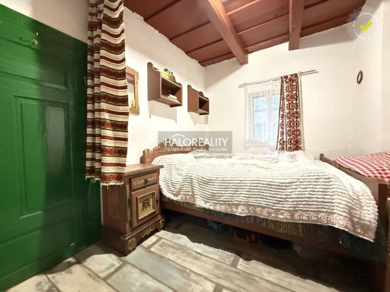 A rustic room in a cottage with a bed, a cabinet, and a wooden decor floor.