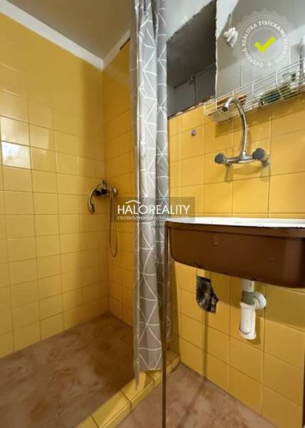 A shower corner in a cabin with bright yellow tiles and a gray curtain.