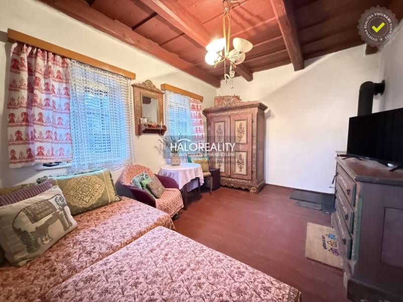 A living room in a cottage with traditional wooden furniture and decorative curtains.
