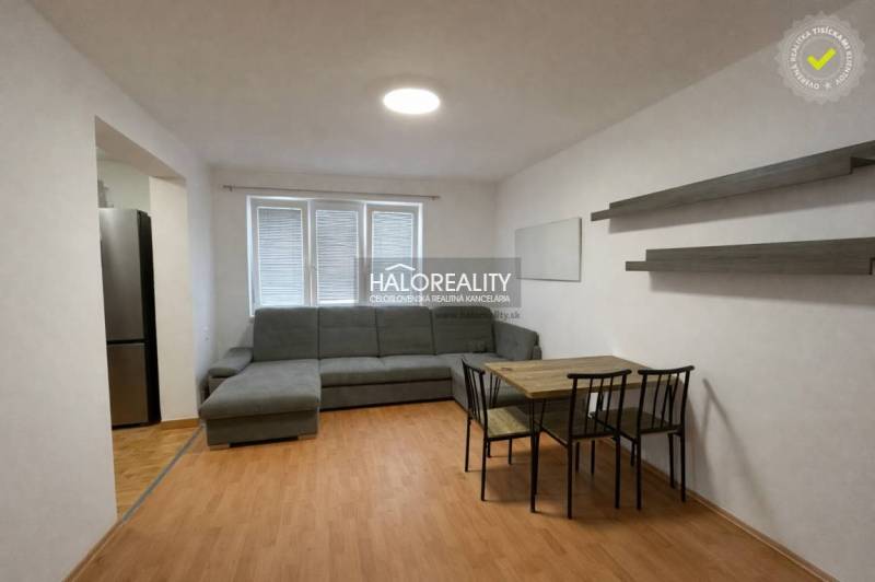 Living room in a 4-room apartment with a wood-patterned floor, sofa, and dining table.