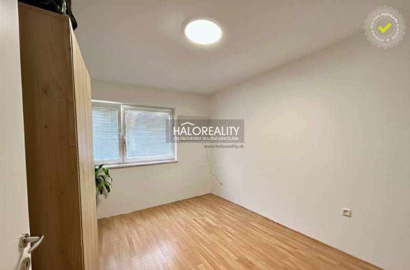 An empty room in a 4-room apartment with a wood-patterned floor and a built-in wardrobe.