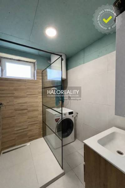 Bathroom in a 4-room apartment with a sink, shower, and washing machine, floor with wood decor.