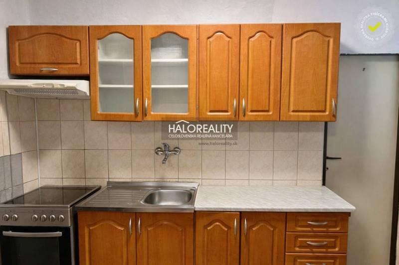 A kitchen with wooden cabinets and a stainless steel sink in a 4-room apartment.
