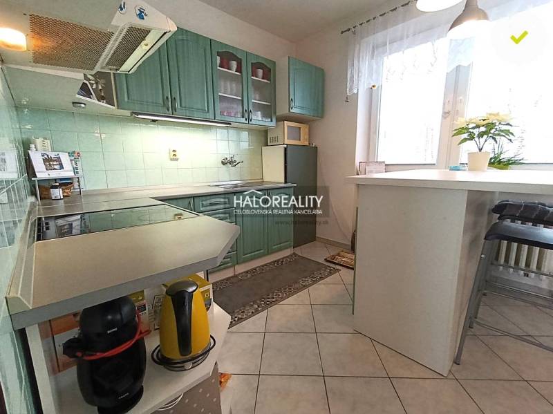 A kitchen in a family house with a bar counter, green cabinets, and decorations.