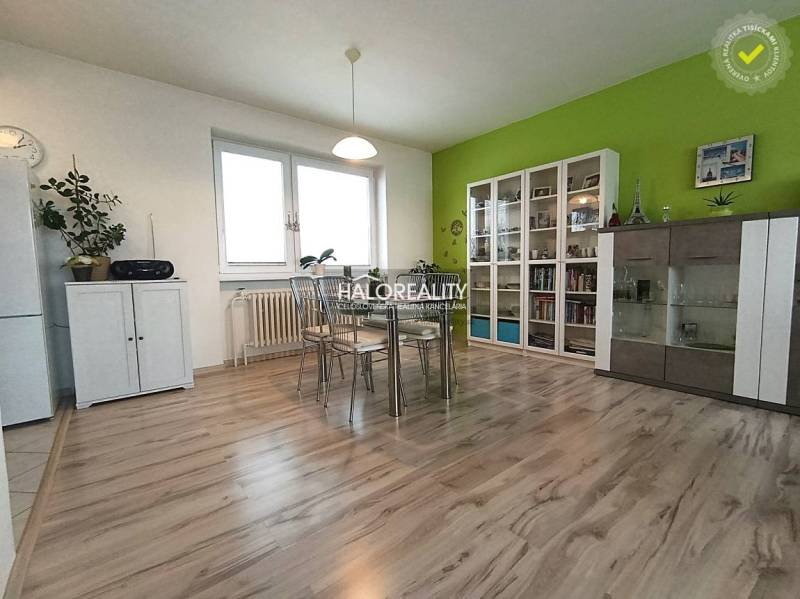 Dining room in a family house with a wood-patterned floor and a green wall.