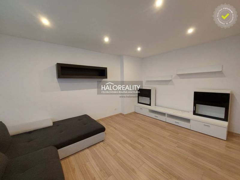 Living room in a two-room apartment with a sofa and wooden decor flooring.