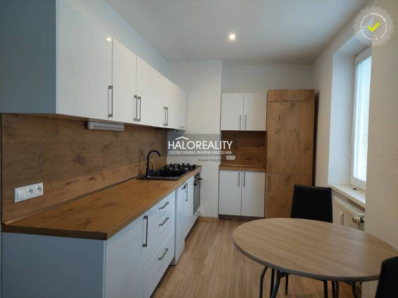 A kitchen with white cabinets and a wood-patterned floor in a two-room apartment.