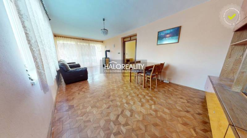 Living room with wood-patterned flooring, a sofa, and a dining table in a family house.