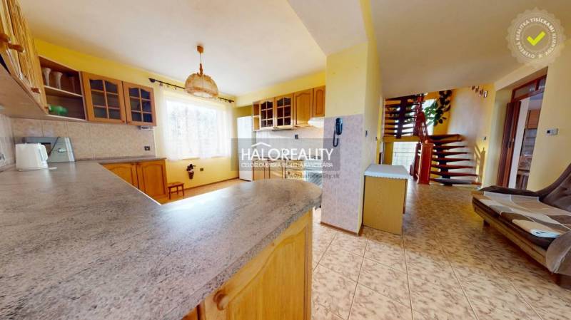 A kitchen in a family house with a living room, staircase, and yellow walls.