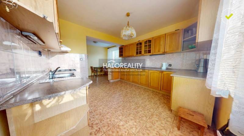 A kitchen with wooden cabinets and ceramic flooring in a family house.